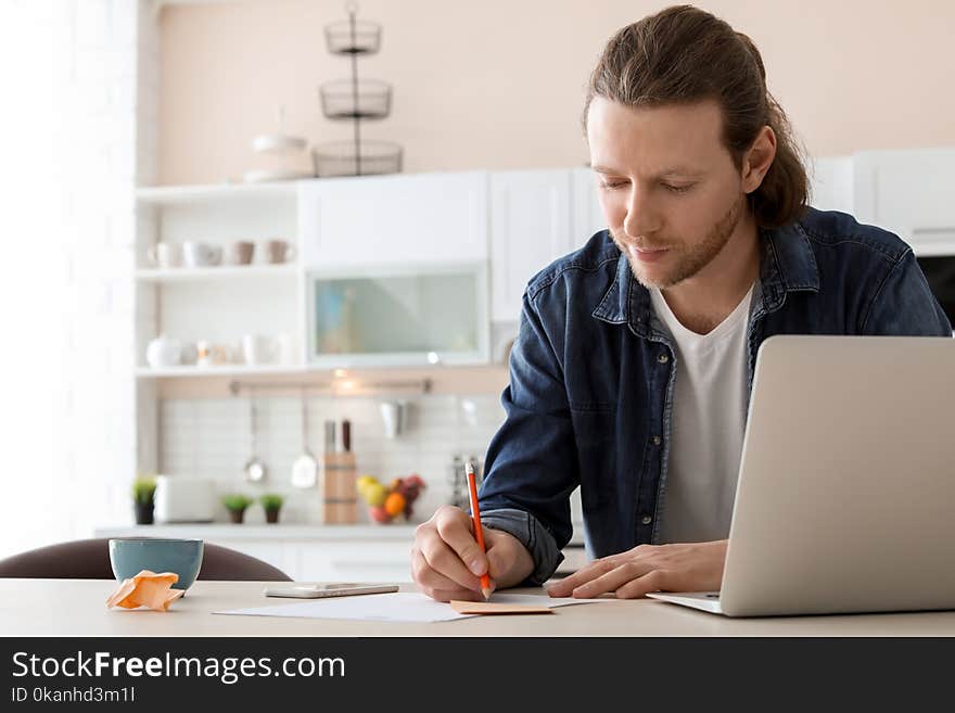 Young Man Working With Laptop At Desk In Home