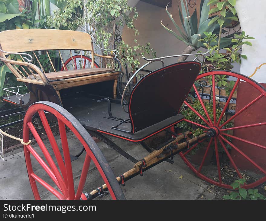 This vintage wooden and iron buggy has painted red wheels. This vintage wooden and iron buggy has painted red wheels.