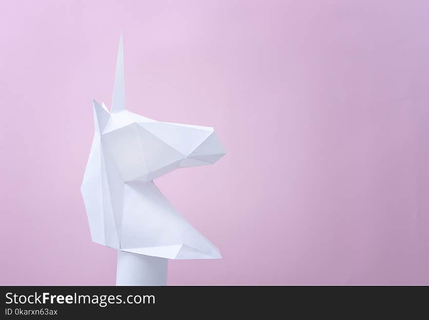 White paper unicorn on a pink background. Space for text.