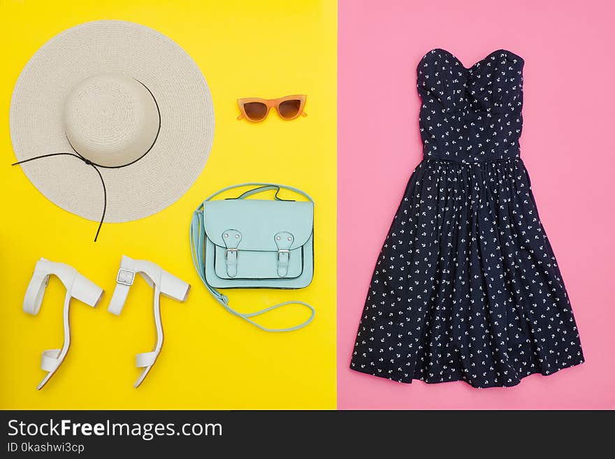 Fashionable concept. Female summer wardrobe. Straw hat, sundress, handbag and shoes. Yellow and pink background, top view