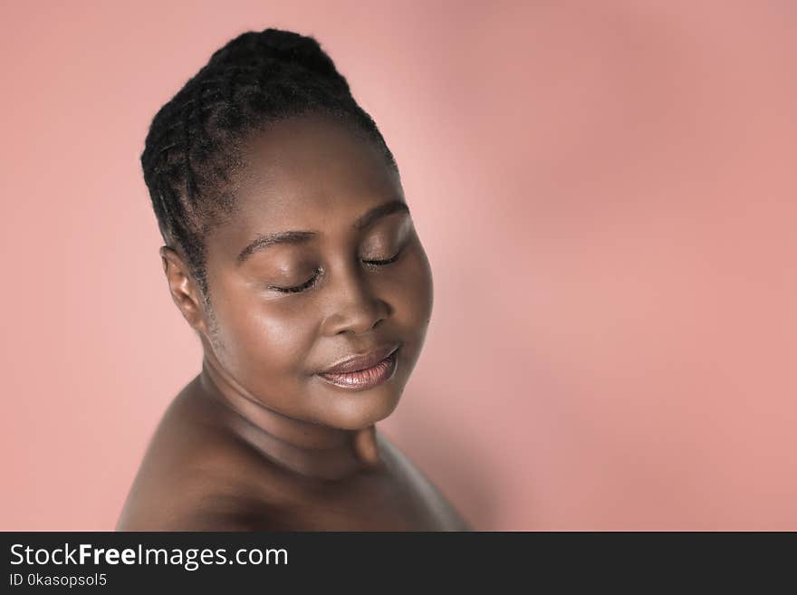 Attractive young plus size African woman with beautiful skin standing with her eyes closed against a blooming dahlia colored background. Attractive young plus size African woman with beautiful skin standing with her eyes closed against a blooming dahlia colored background