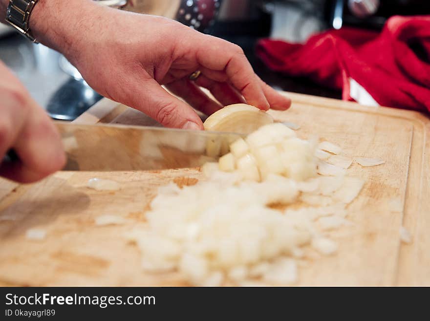 Close up shot of a mature man cutting up an onion on a chopping board inthe kitchen of his home. Close up shot of a mature man cutting up an onion on a chopping board inthe kitchen of his home.