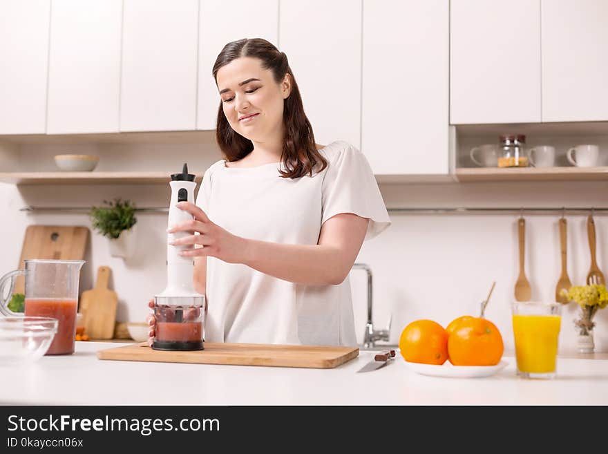 Pleased appealing woman making smoothie