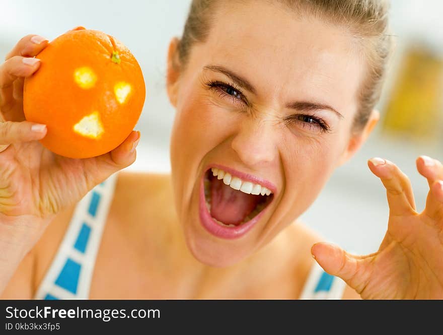 Young woman scaring with orange with hallowing face