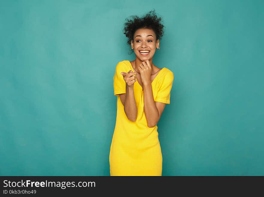 Smiling african-american woman pointing to camera, at blue studio background, copy space. Smiling african-american woman pointing to camera, at blue studio background, copy space