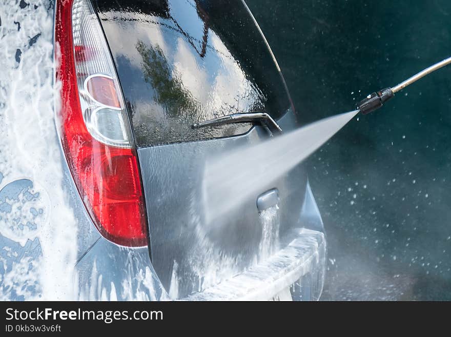 Car Wash Closeup. Washing Car by High Pressure Water.