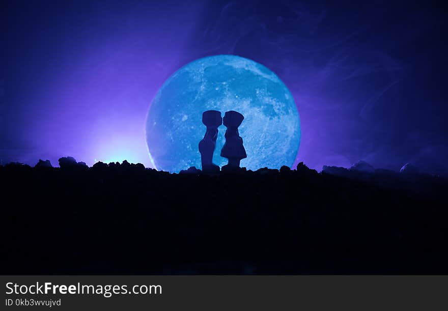 Silhouette of couple kissing under full moon. Guy kiss girl hand on full moon silhouette background. Valentine`s day decor concept. Silhouette of loving couple kissing against the full moon