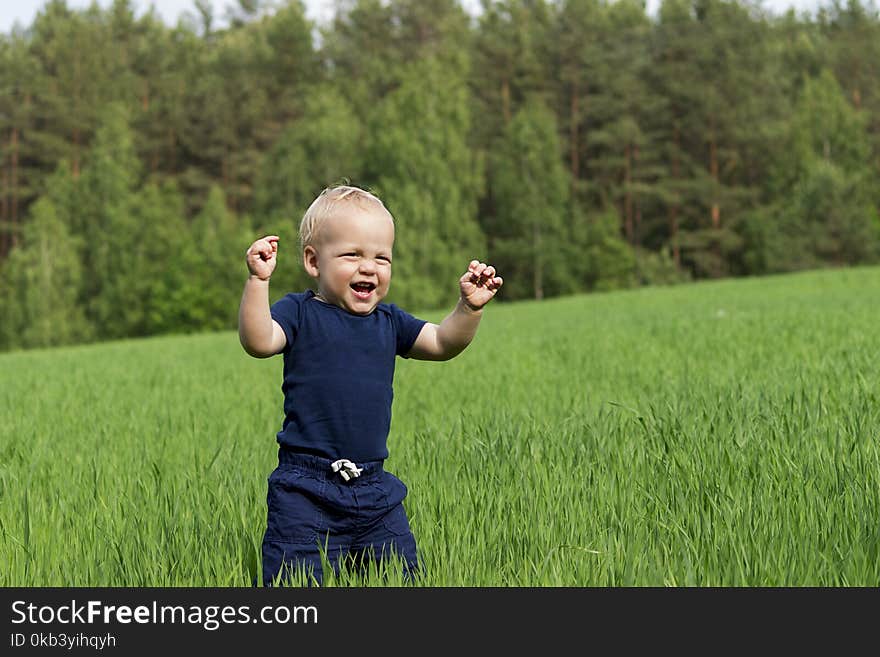 Happiness Baby Boy Sitting On The Grass In Field