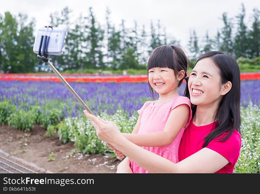 Mother and daughter selfie and smile happily with beautiful landscape in Shikisai-no-oka. Mother and daughter selfie and smile happily with beautiful landscape in Shikisai-no-oka