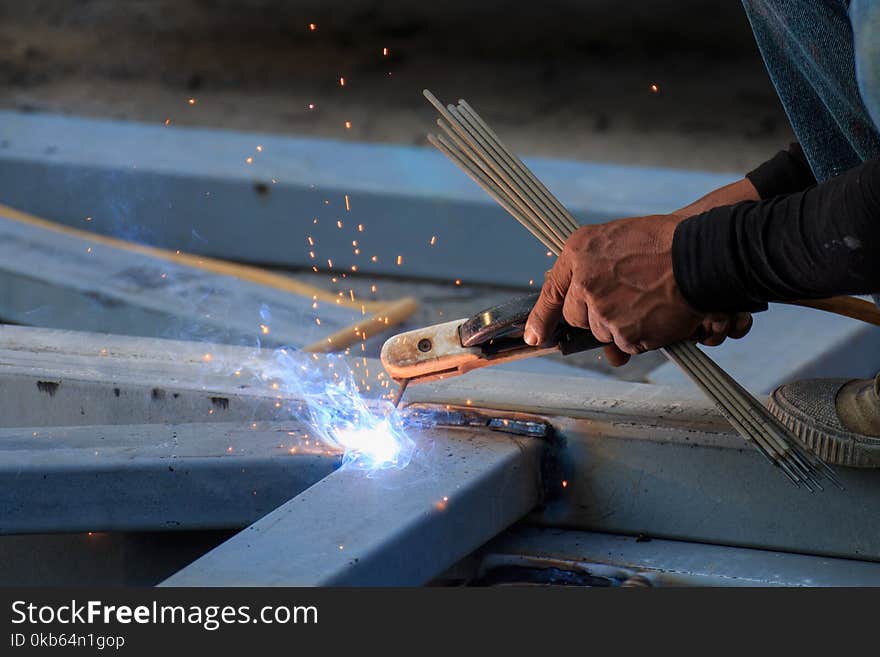 Asian worker making sparks while welding steel