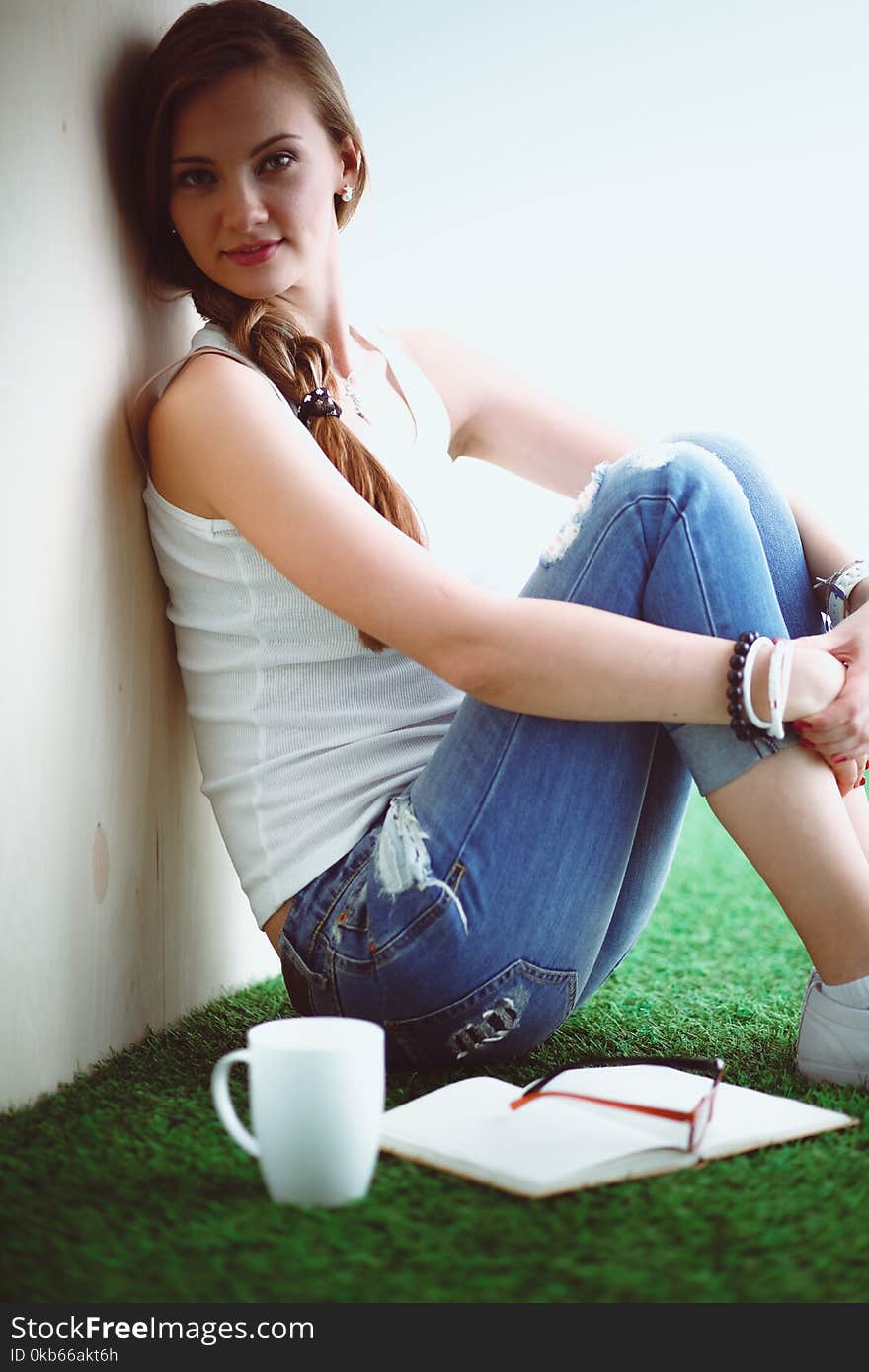 Beautiful woman sitting on the floor and holding a cup . Beautiful woman.