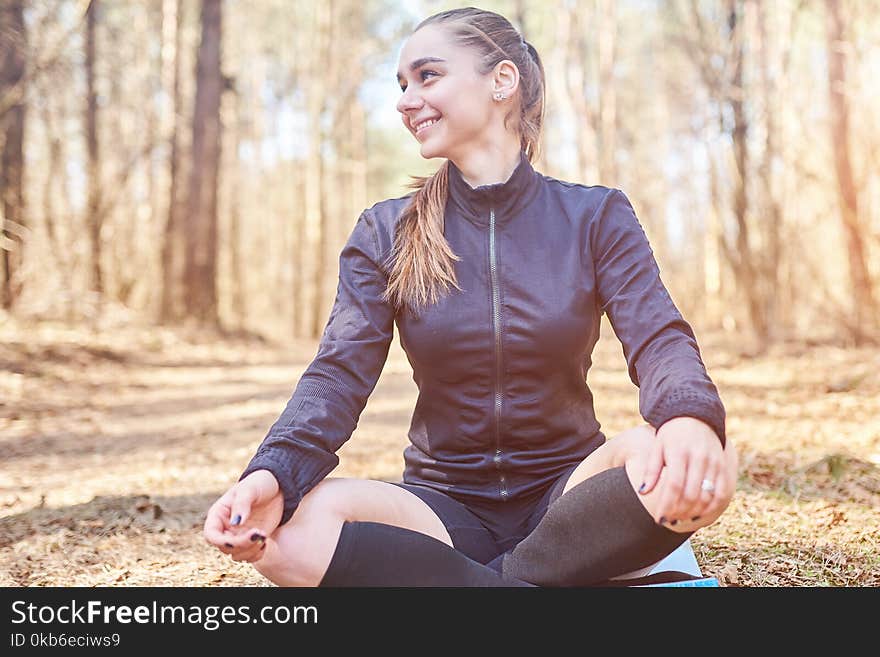 Sporty girl in Lotus pose smiling in the woods for any purpose