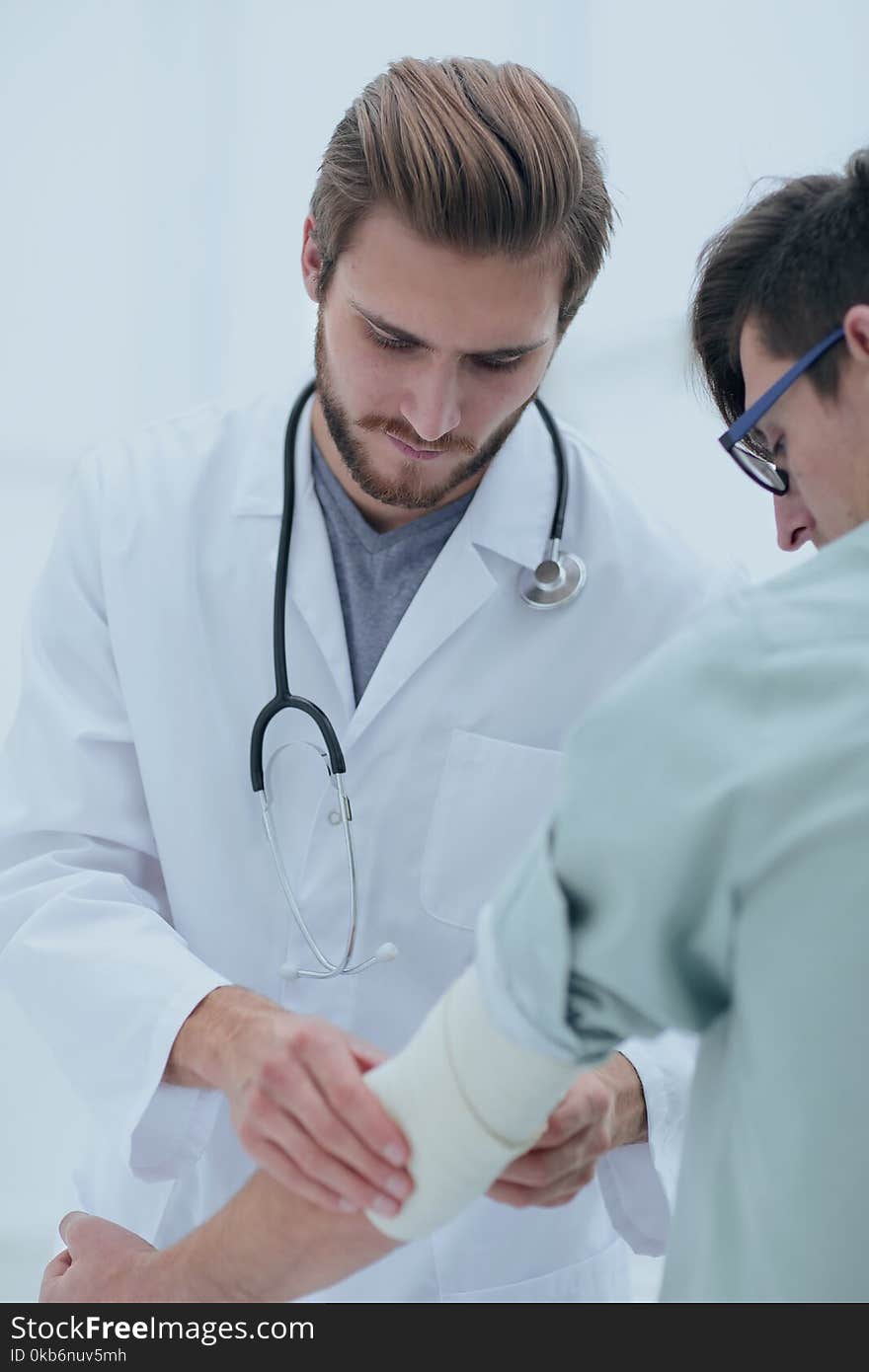 Orthopedist applying bandage onto patient`s arm.doctor and the patient