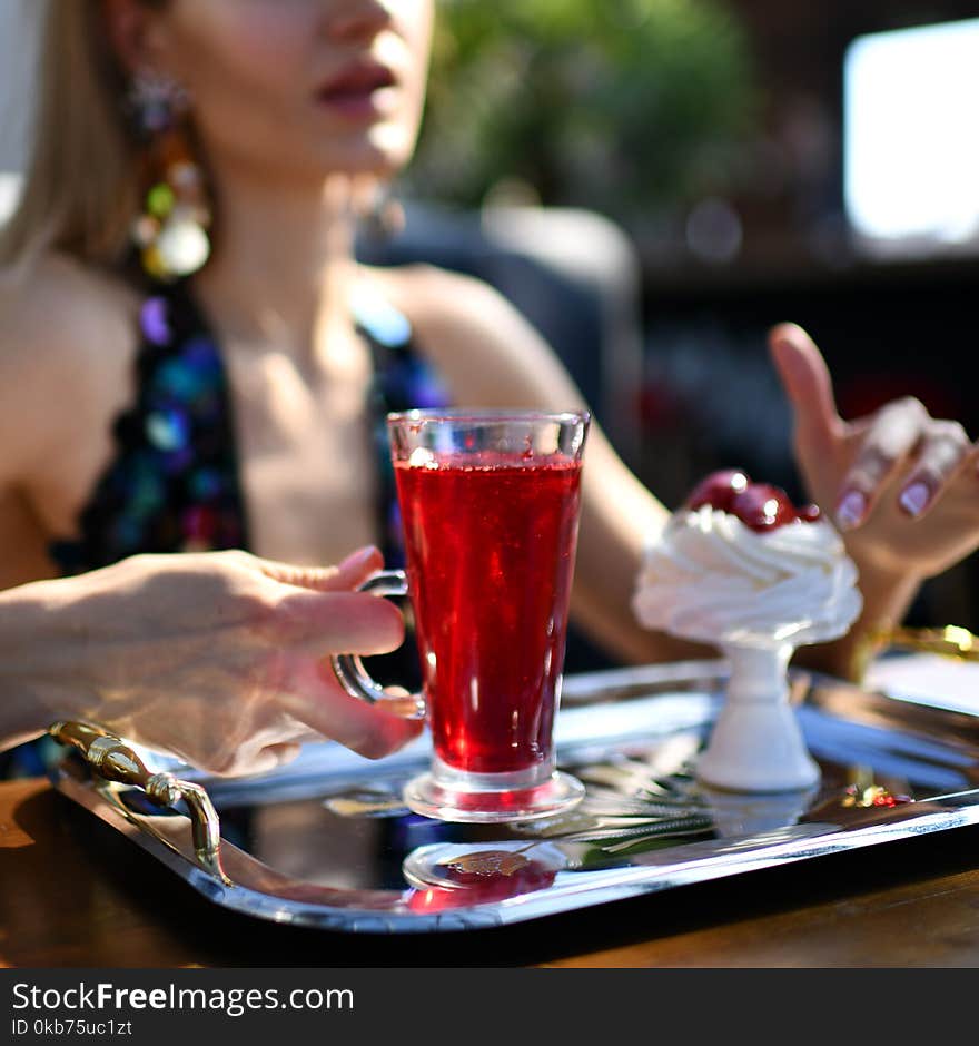 Woman in expensive interior restaurant cafe drinking red margarita cocktail or juice tea and eat dessert cake with strawberry