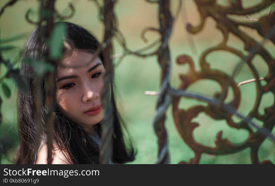 Woman With Green Background Near Black Metal Gate