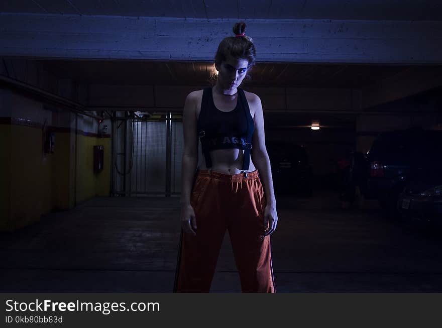 Woman With Black Sports Bra and Red Pants in Dark Room