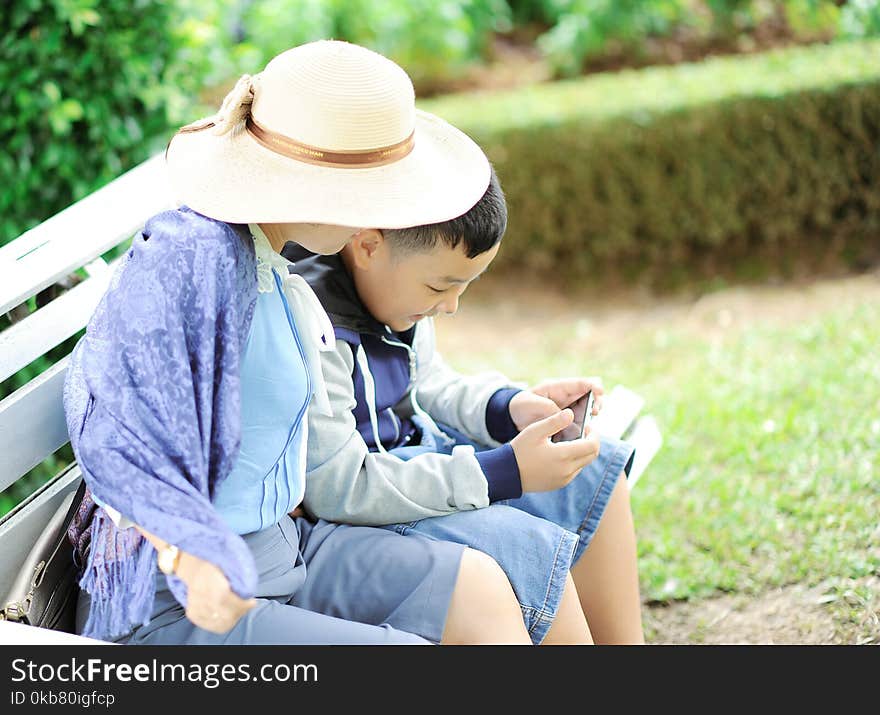 Woman With a Boy Sits on Bench