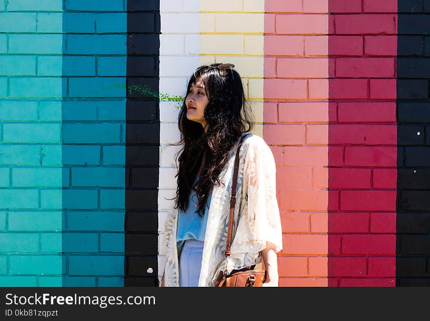 Woman Wearing White Cardigan Standing Beside Multicolored Wall