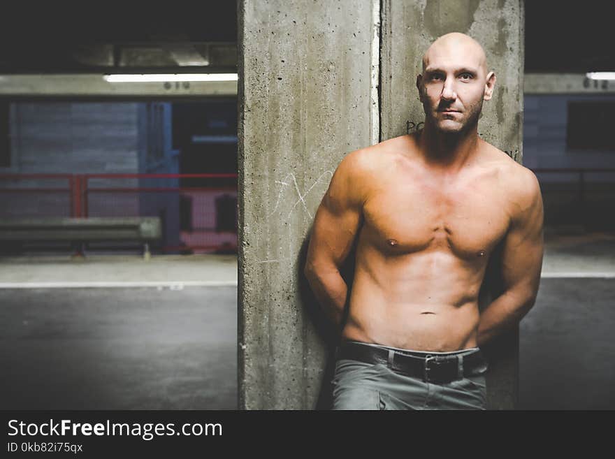 Photography of a Shirtless Man Leaning on Wall