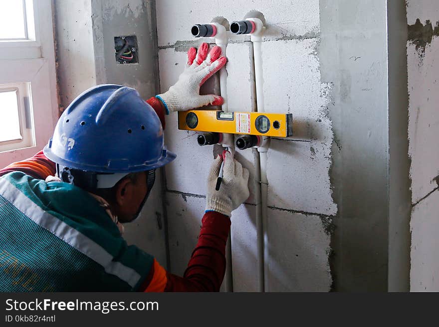 Person Wearing Blue Hard Hat Holding White Plastic Water Pipe