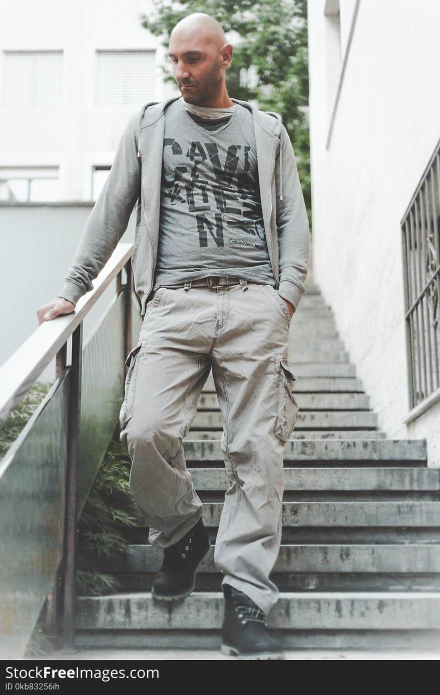 Photo of Man Wearing Grey Zip-up Jacket and Brown Cargo Pants Walking Down on Concrete Stairs