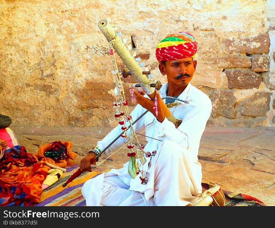 Man In White Long-sleeved Thawb Holding A Musical Instrument