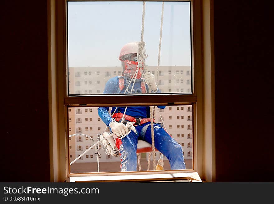 Man Wearing Orange Safety Strap in Front of a Windowpane