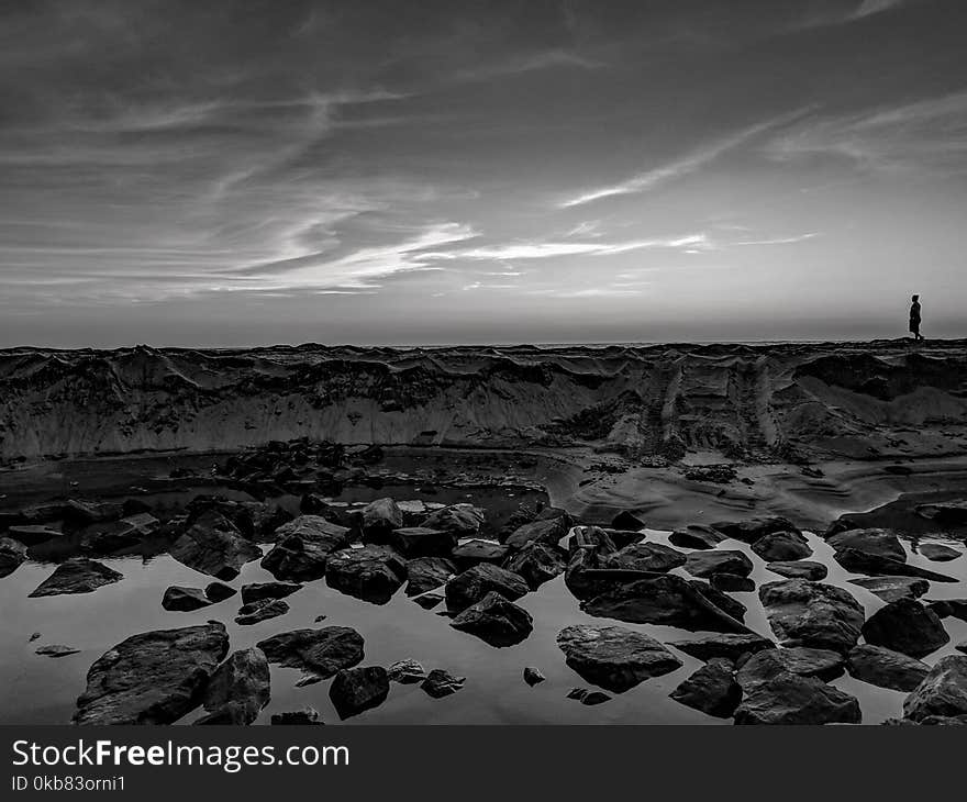 Grayscale Photo Of Person Walking On Rocks