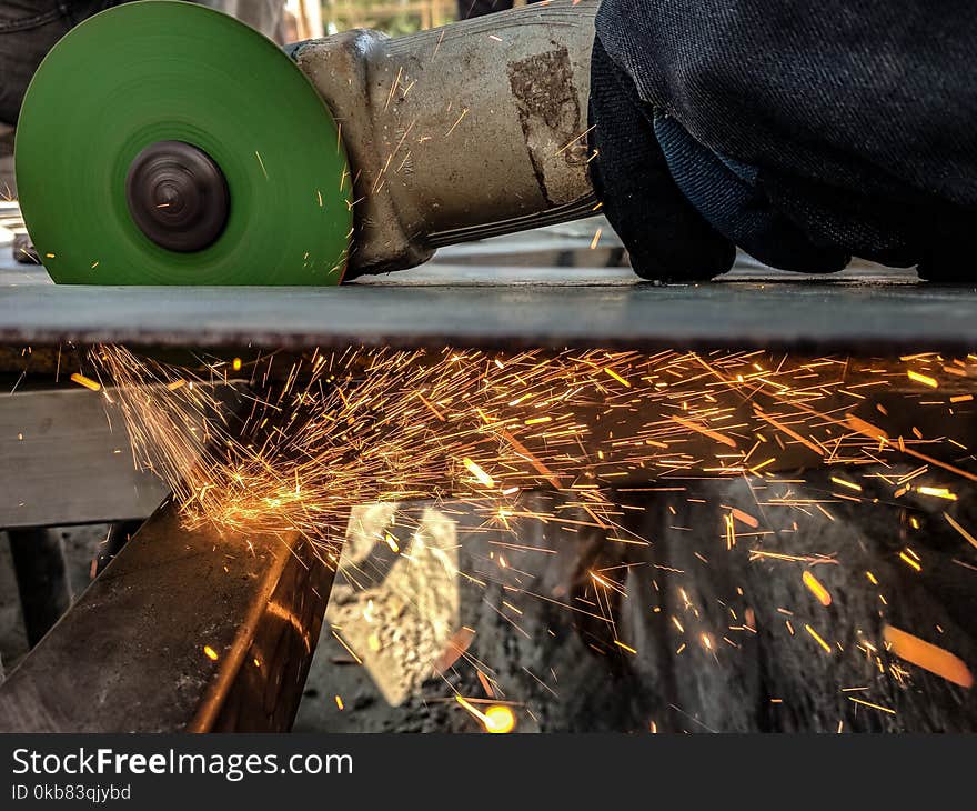 Person Using Green And Grey Angle Grinder On Sheet Of Metal