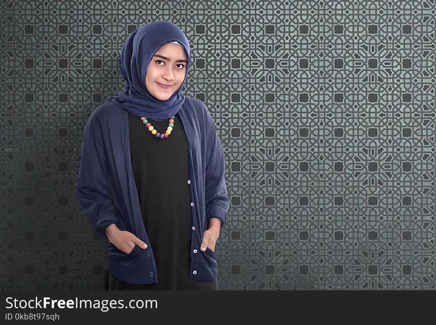 Smiling asian muslim female standing with traditional dress over abstract background