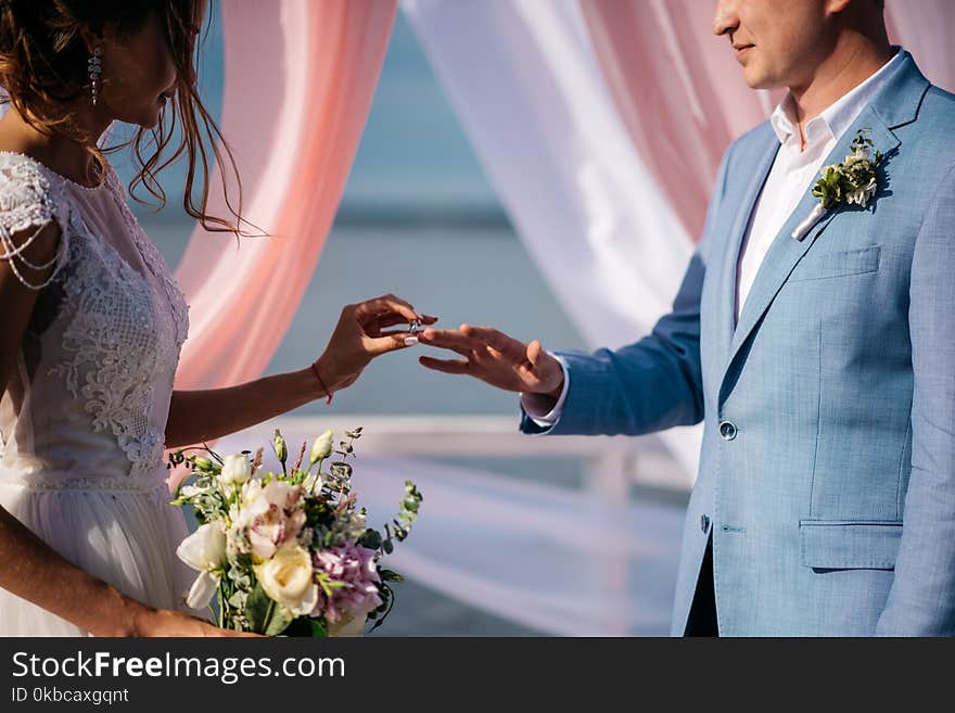 The bride and groom are exchanging wedding rings on the pier. The bride and groom are exchanging wedding rings on the pier