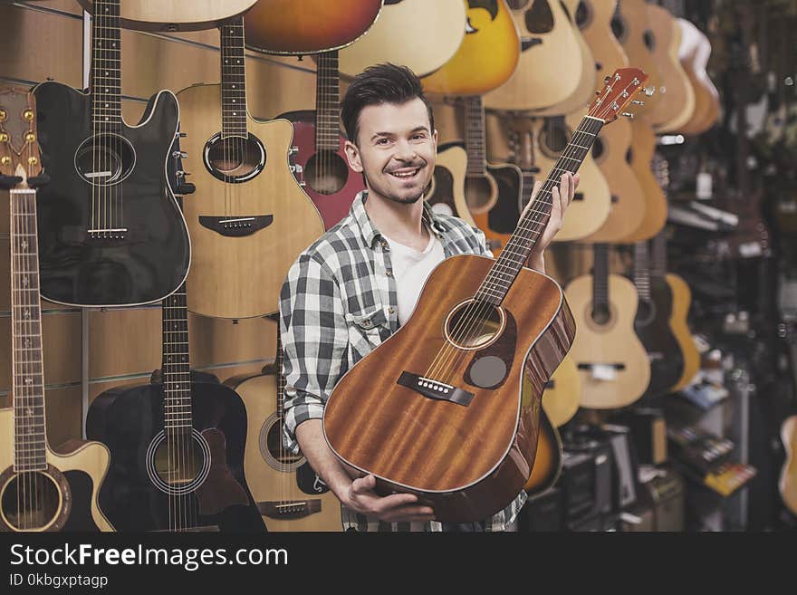 Man is showing guitar in music store.