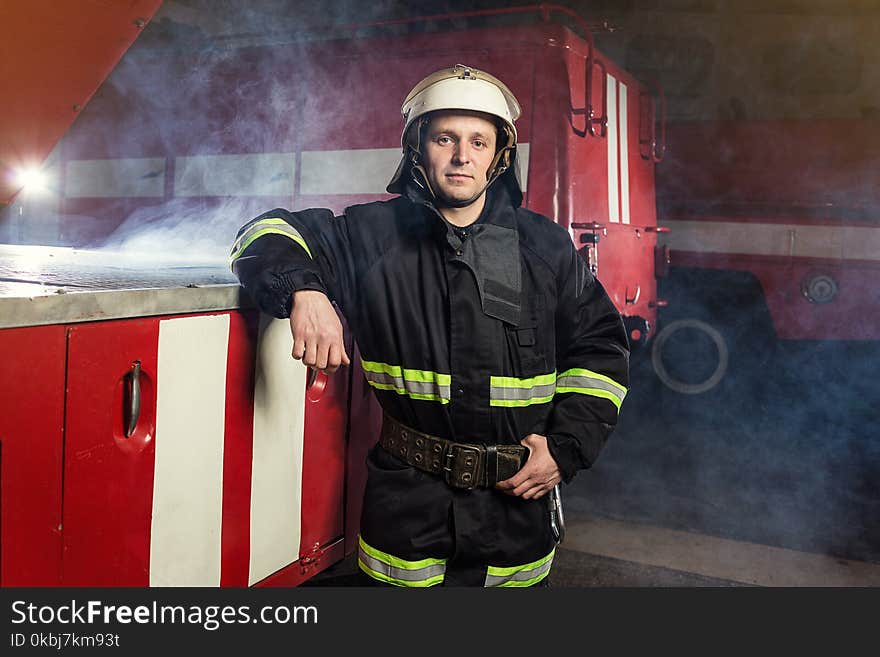 Fireman firefighter in action standing near a firetruck. Emergency safety. Protection, rescue from danger.