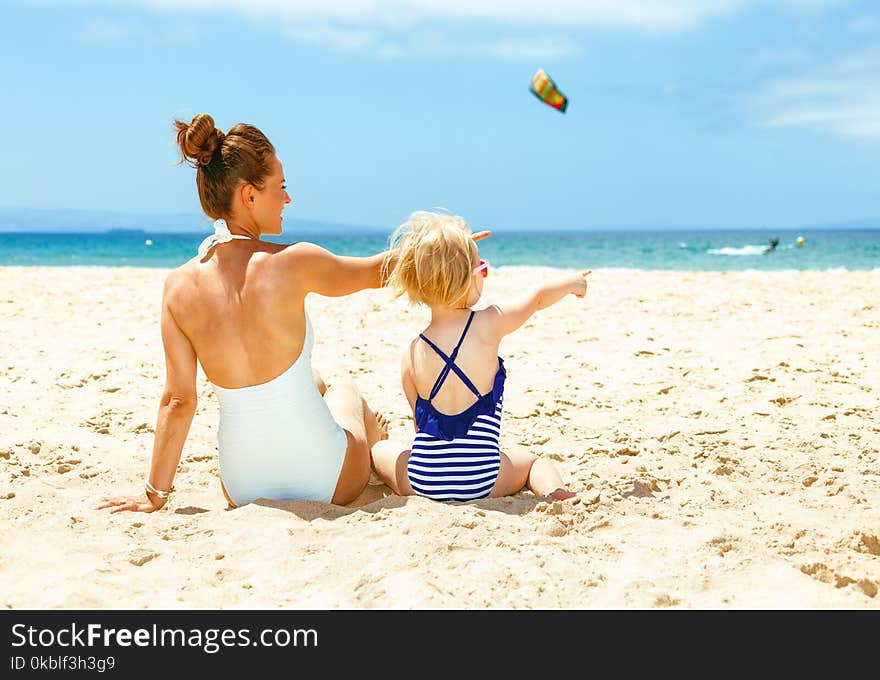 Modern mother and child on beach pointing at something