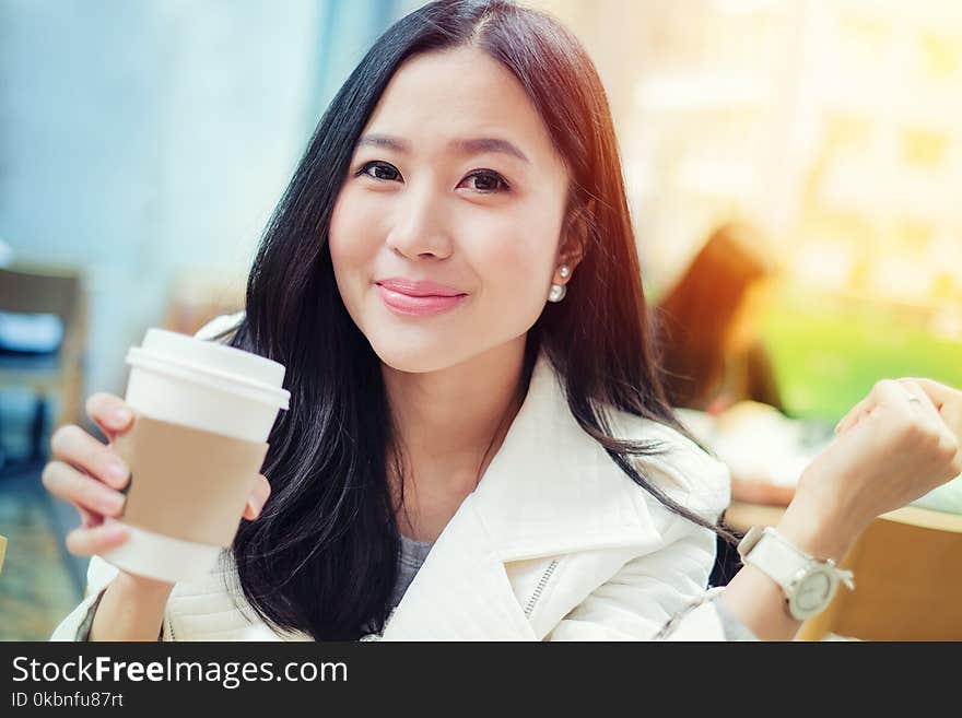 Woman drinking coffee at coffee shop with sunrise streaming