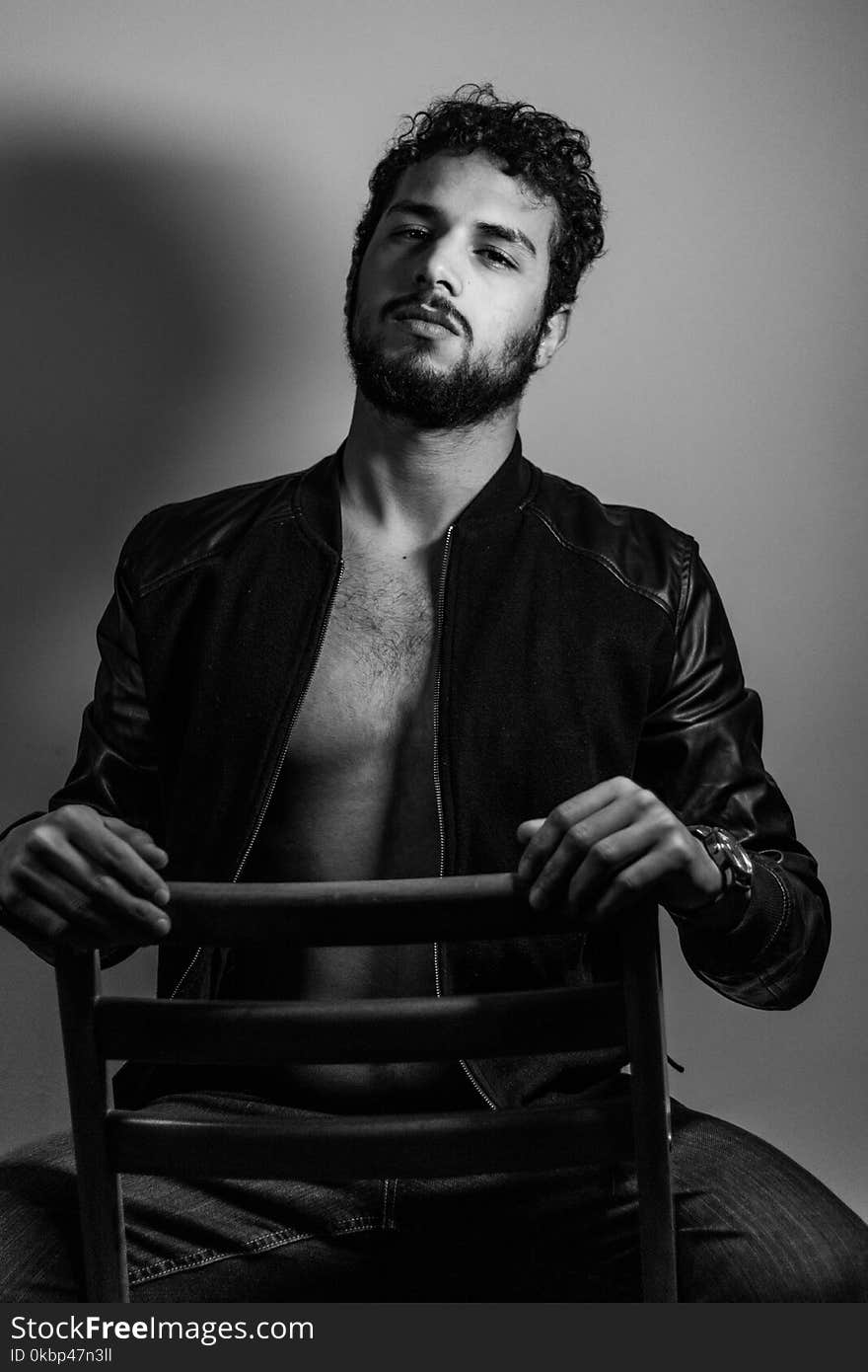 Grayscale Photo of Man Sitting on Ladder-back Chair