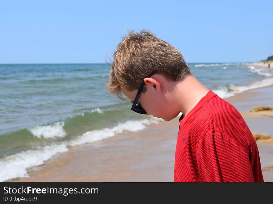 Photo of Boy Wearing Red Shirt and Sunglasses On Seashore