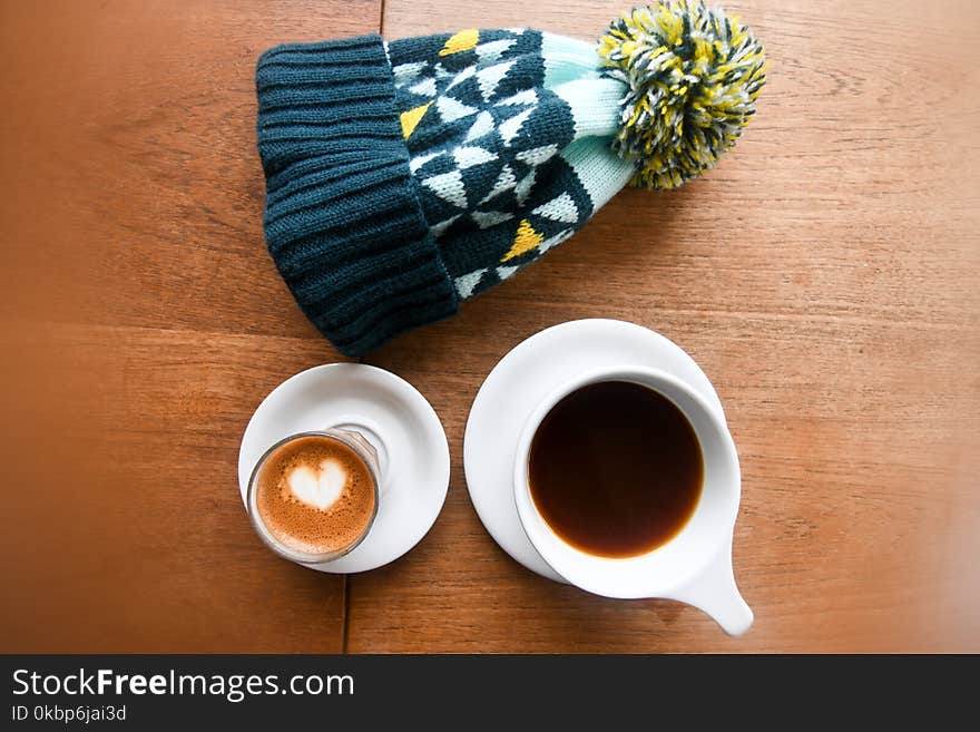 High Angle Photo Of Mug Filled With Coffee Beside Bobble Hat