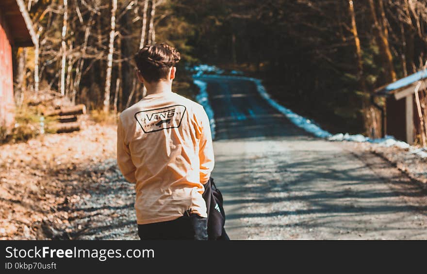 Person Wearing Beige Vans Long-sleeved Shirt Near House