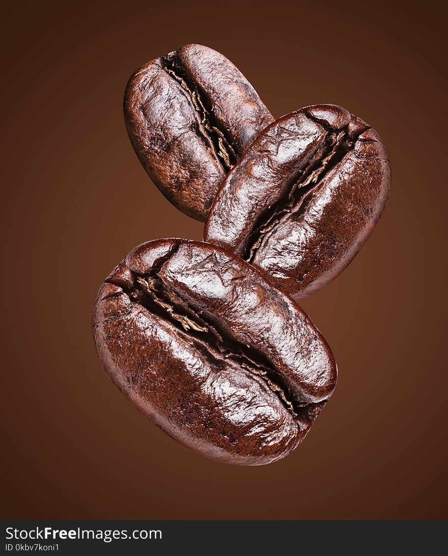 Three roasted coffee beans on the brown background. File clipping path. Three roasted coffee beans on the brown background. File clipping path.