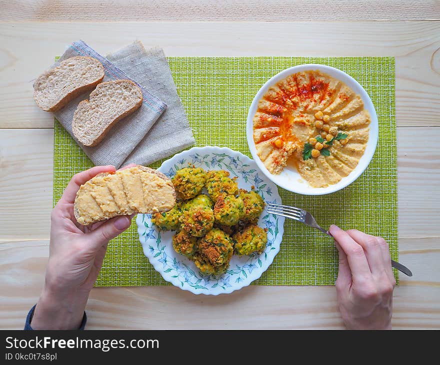 A plate of hummus and parsley on wooden background. The view from the top. A plate of hummus and parsley on wooden background. The view from the top.