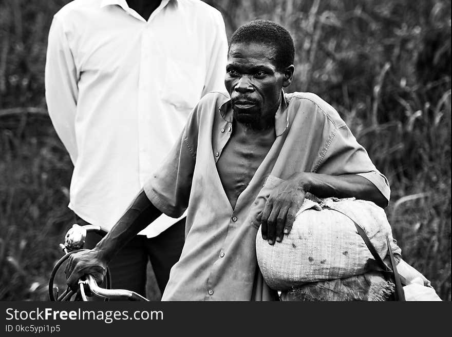 Grayscale Photography of Man in Button Shirt Walking Behind Man in Button Shirt