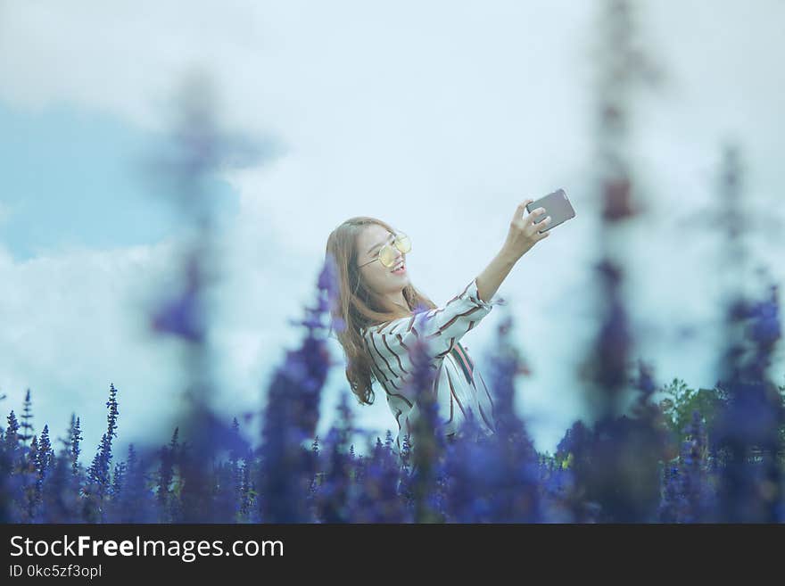 Woman in Black and White Dress Shirt Taking Photo on Lavender Flower Field at Daytime