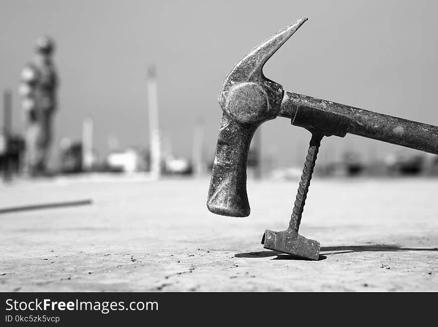 Grayscale Photo of Hammer on Pavement