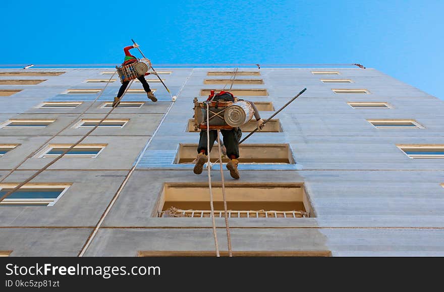 Two People Wearing Harnesses and Painting Building