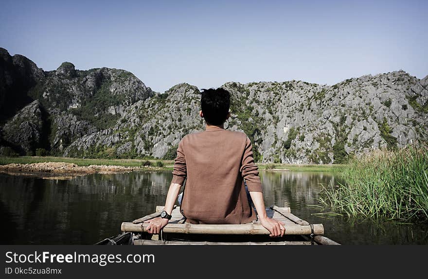 Man Sitting on Bridge Front of Mountain