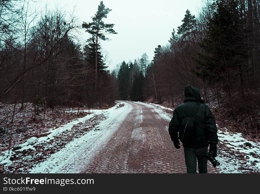 Person in Black Hoodie Top and Black Pants on the road holding a camera