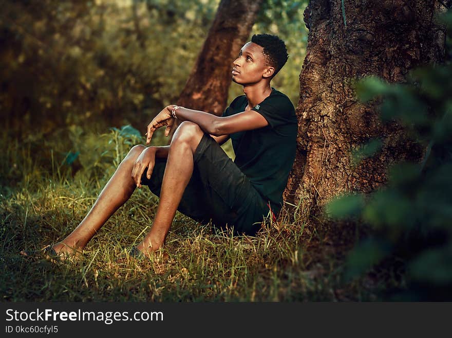 Man Seating Beside Tree Trunk