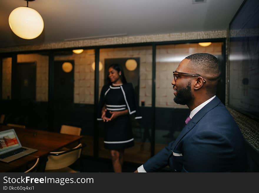 Man in Blue Formal Suit Jacket Sitting Near Standing Woman