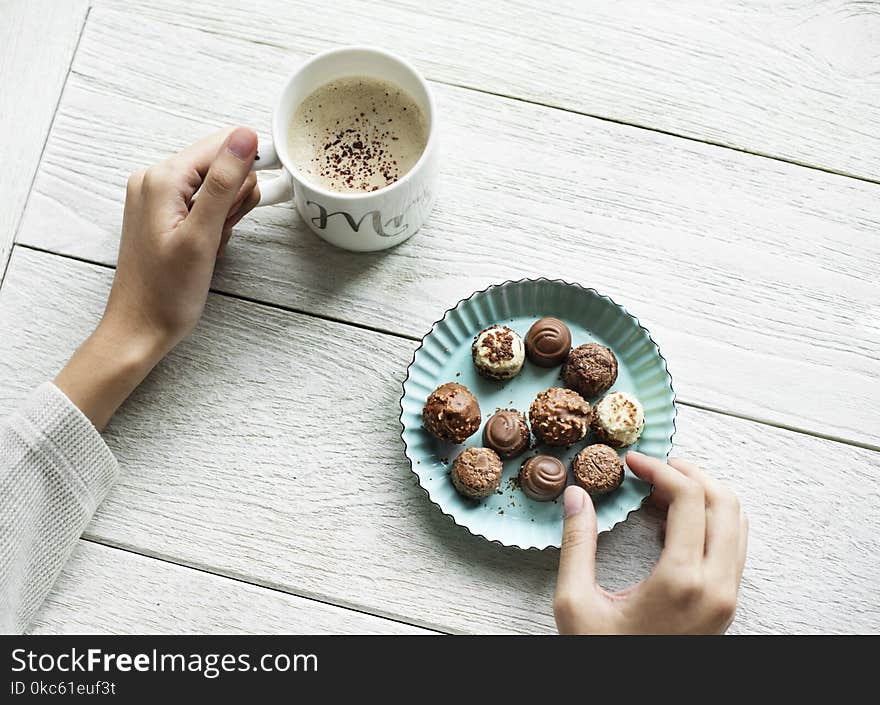 Person Holding Chocolates And White Ceramic Mug